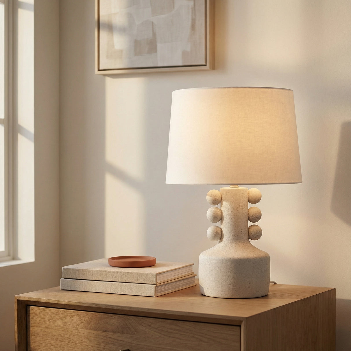 Mia Ceramic Table Lamp, Speckled White beaded Table Lamp in a Modern Bedroom with a light oak nightstand and abstract framed art.