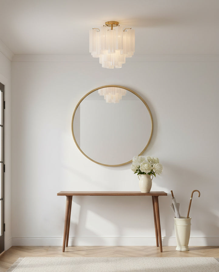 Grace Semi-Flush 18, Brass with White Glass - A brass semi-flush mount light with white glass shades hangs above a wooden console table with a round gold mirror and a vase of white flowers.