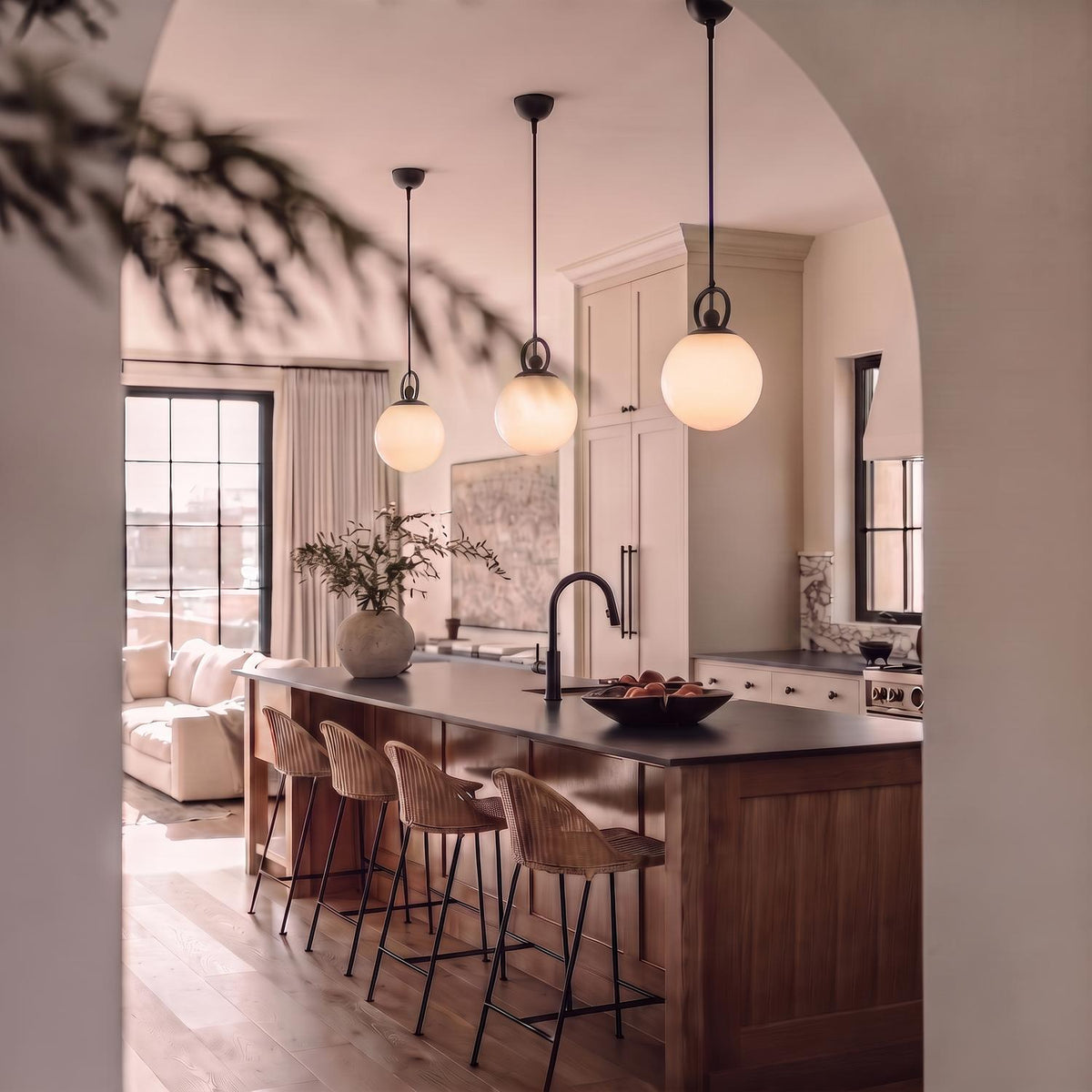 A transitional kitchen with three matte black and opal glass globe pendants suspended over a dark wood island lined with woven barstools.