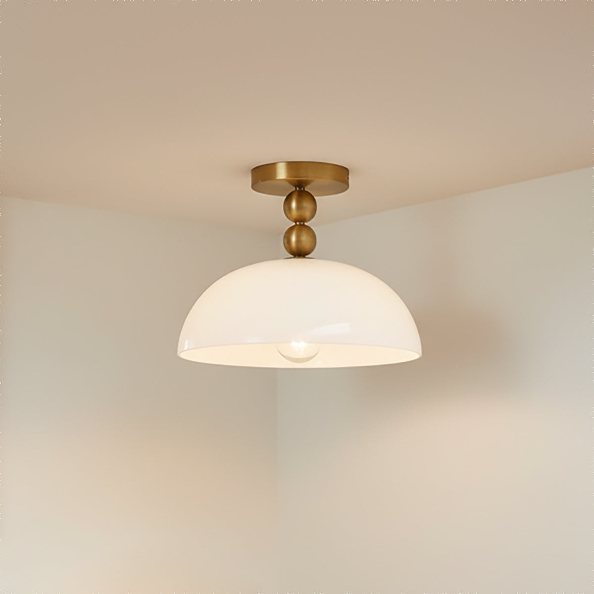 Archie Flush Mount 12", Brushed Brass and Opal Glass - A close up of the fixture against a white ceiling