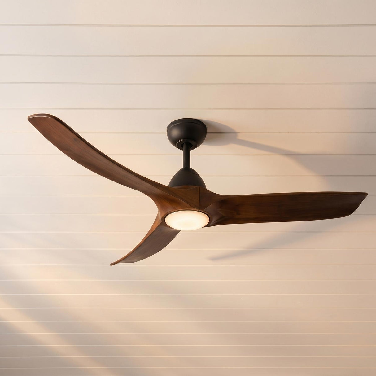 A modern living room featuring the Sedona LED Ceiling Fan 60" in matte black and dark walnut installed in the center of a white shiplap ceiling.
