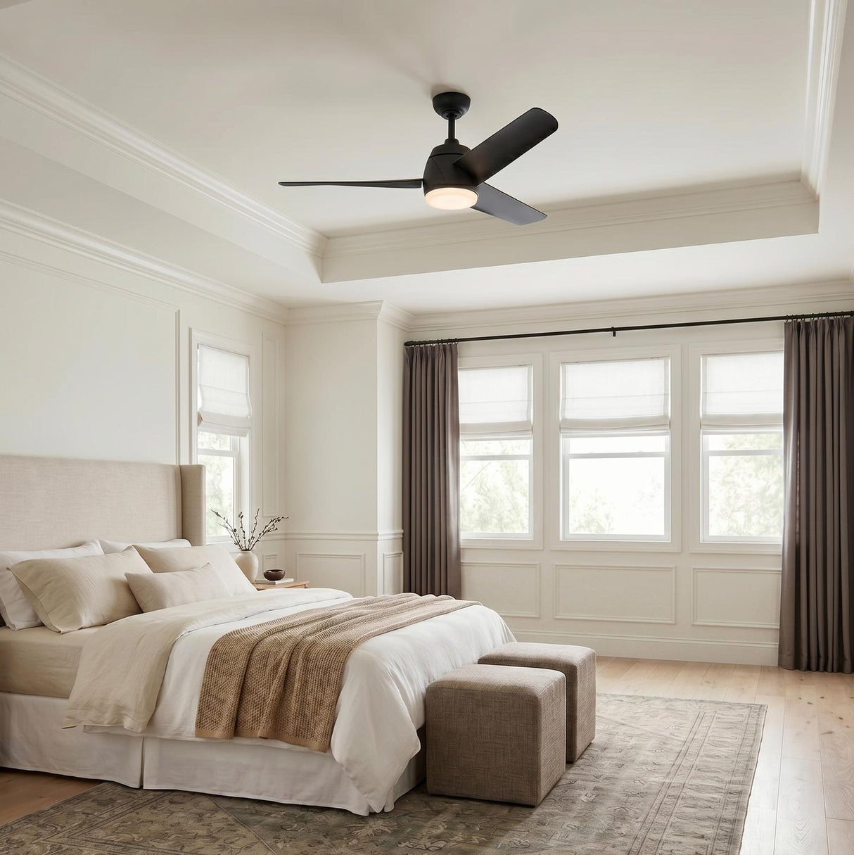 A transitional bedroom with a matte black Lorain LED Ceiling Fan 54" centered in a coffered ceiling above an upholstered bed and large windows with taupe curtains.
