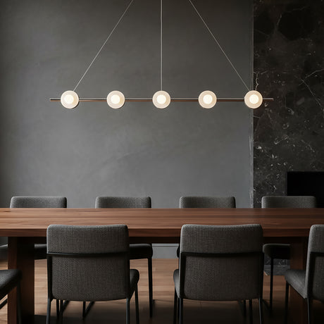 Modern 48" wide pendant light over a long wooden dining table with gray chairs against a dark wall.
