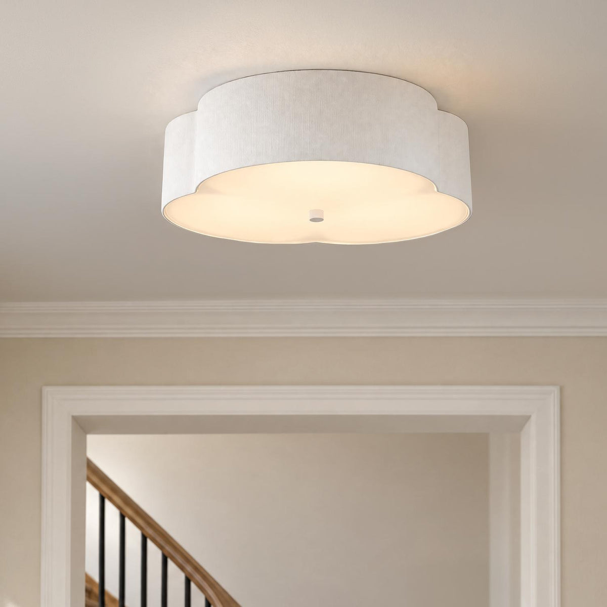A transitional foyer featuring the Shyla Flush Mount 14", Antique White fixture with a scalloped fabric shade mounted above a cased opening leading to a wooden staircase.