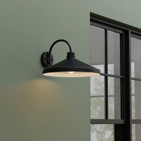 Black wall-mounted outdoor light fixture on a green wall with a window in the background.