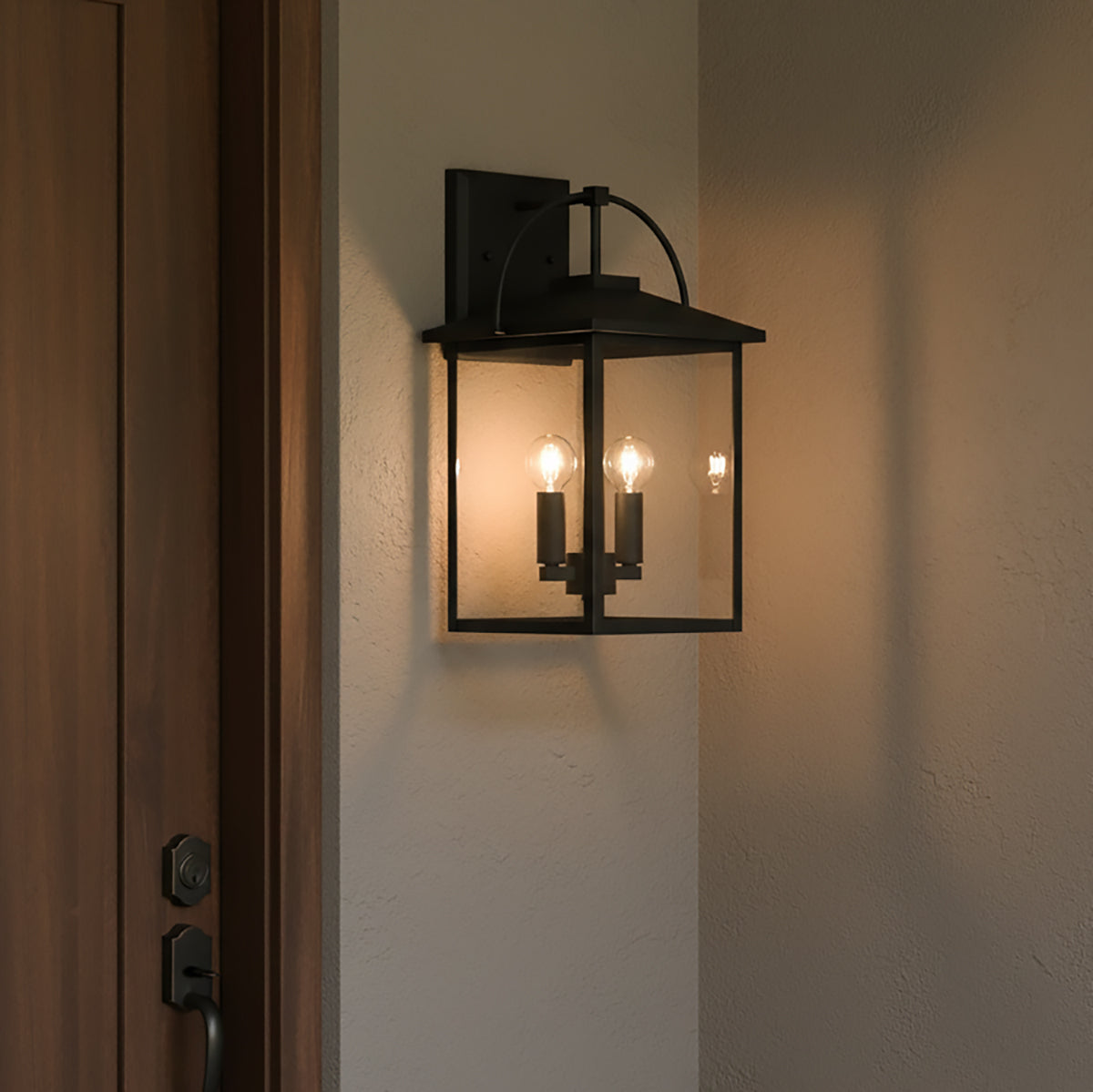 Black wall-mounted outdoor light fixture on a white wall next to a wooden front door.