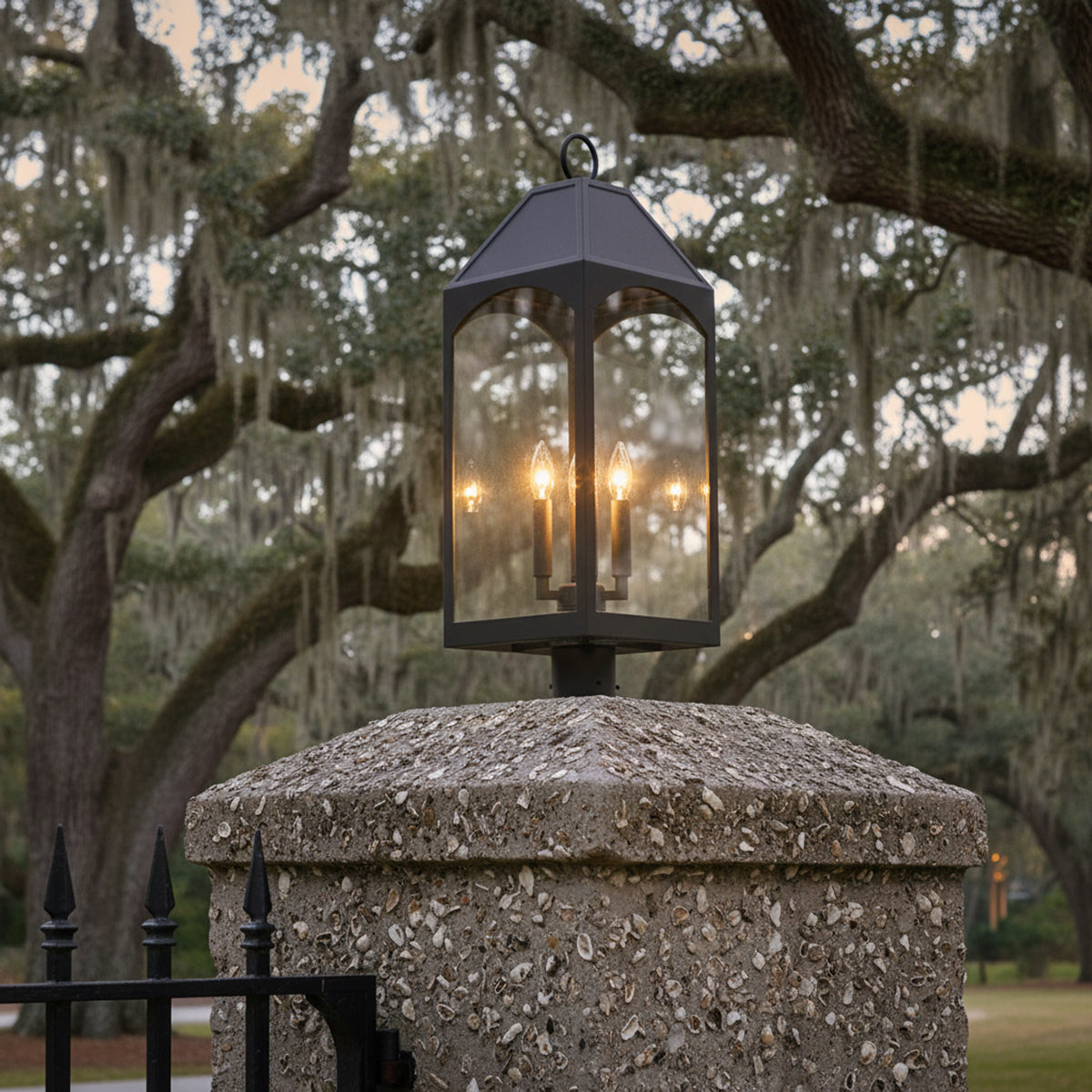 Chester Outdoor Post Light, Black - A black post light fixture is displayed atop a stone column with Spanish moss-draped trees in the background.