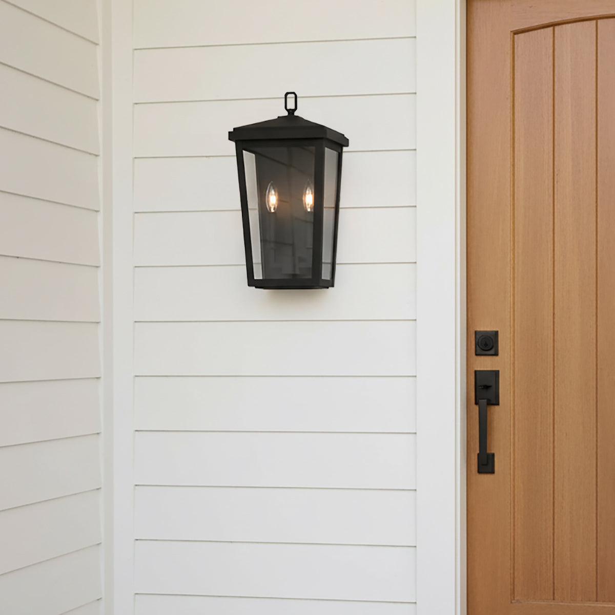 Leighton 18" tall Black outdoor wall light fixture on a white panel wall next to a wooden door.