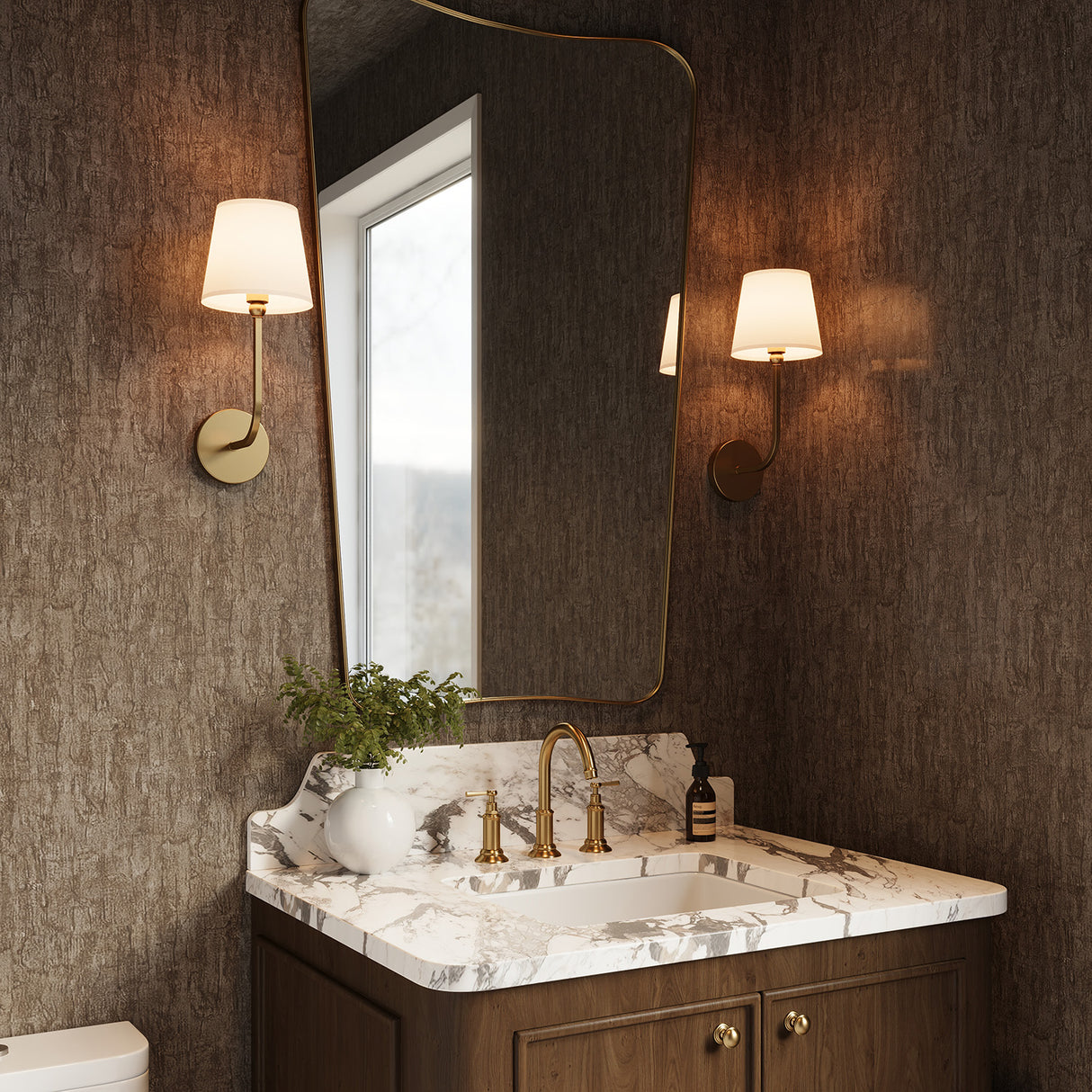 Two Elowen 17" Wall Sconces, Aged Brass finish with white shade flanking a brass vanity mirror in a powder room with brown textured wallpaper