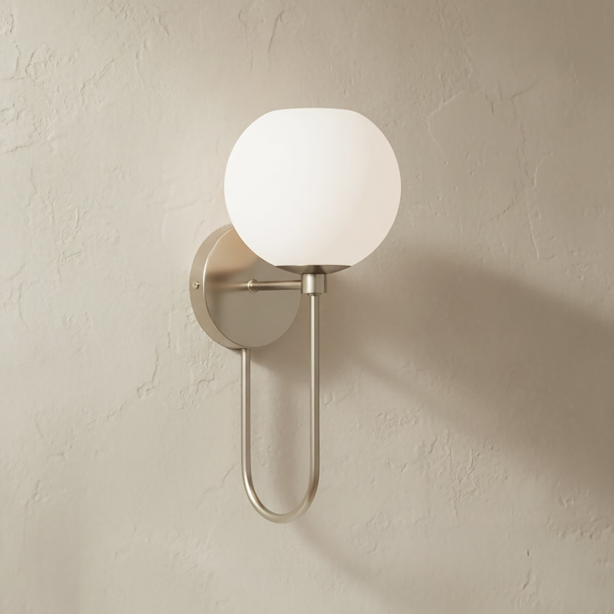 Enid Wall Sconce 15", Brushed Nickel, on a light beige plaster wall.
