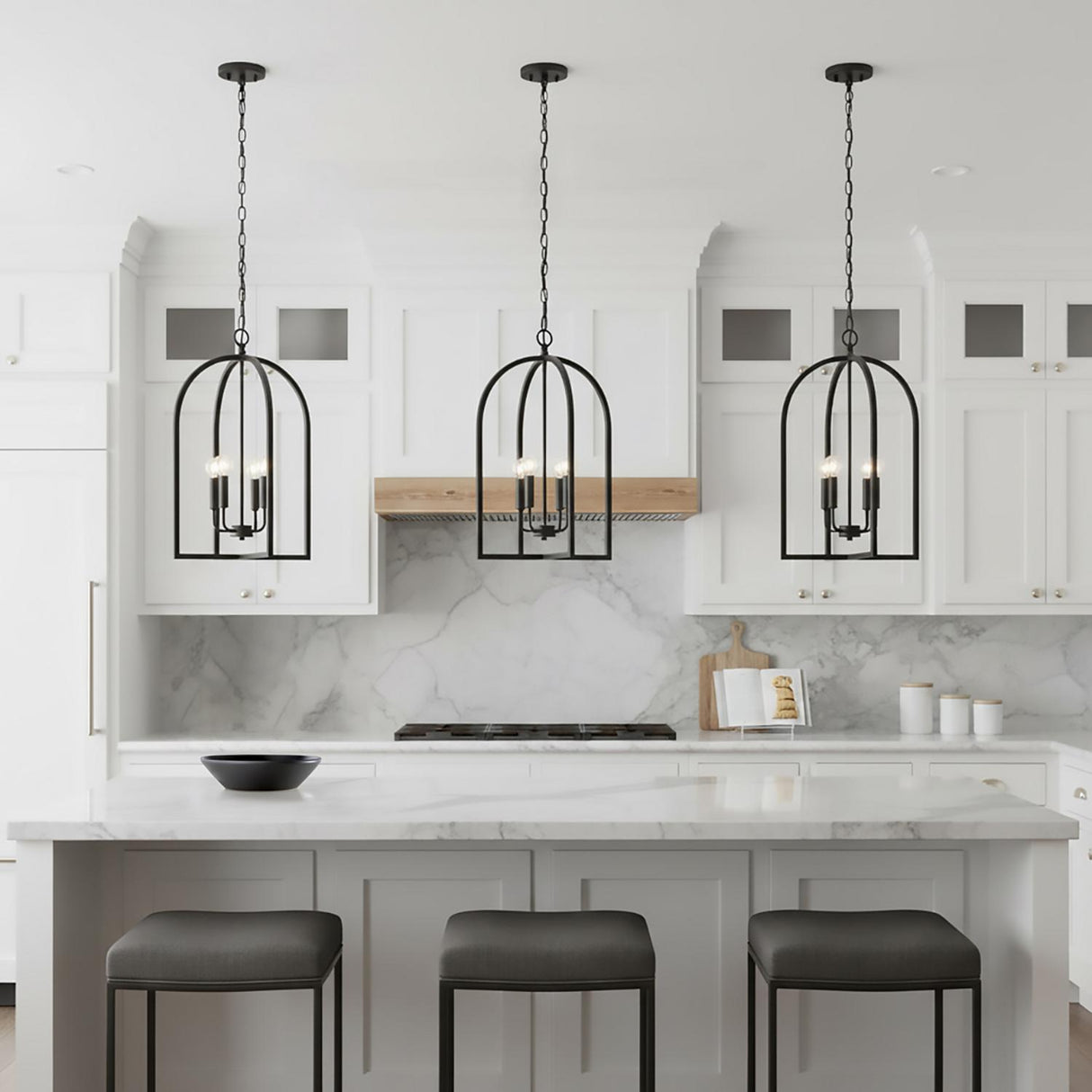 A transitional kitchen features three Elira Lantern Pendant 16", Matte Black fixtures hanging over a white marble island with white shaker cabinets and a matching backsplash.