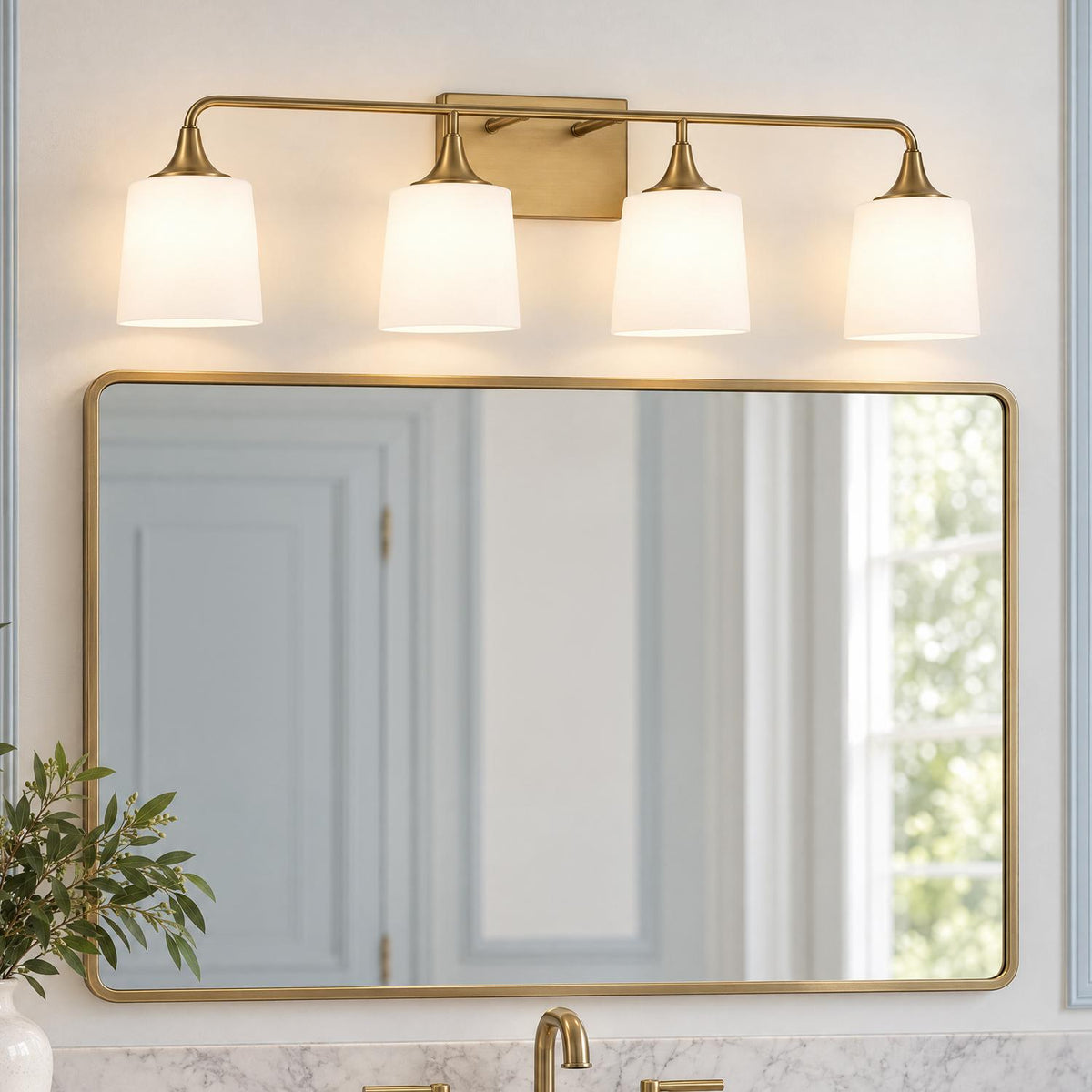 A transitional bathroom features the Harper 4 Light Vanity, Aged Brass with frosted white glass shades mounted above a rounded brass mirror and marble countertop.