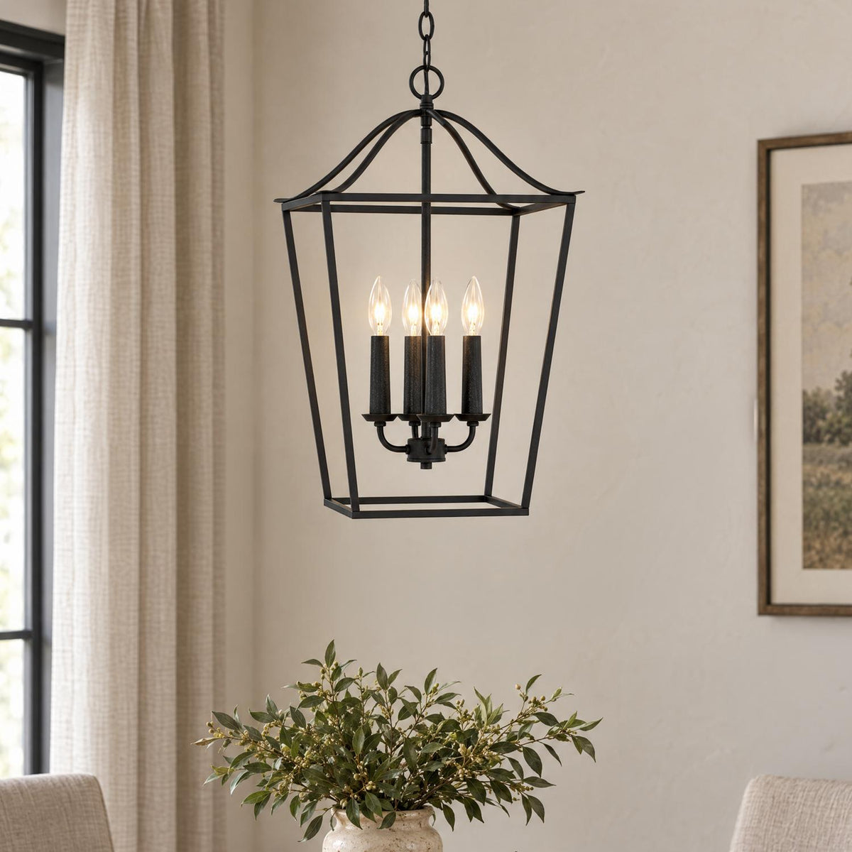 A transitional dining room with the Eloise Lantern Pendant 16", Textured Black hanging over a table with green foliage in a ceramic vase.