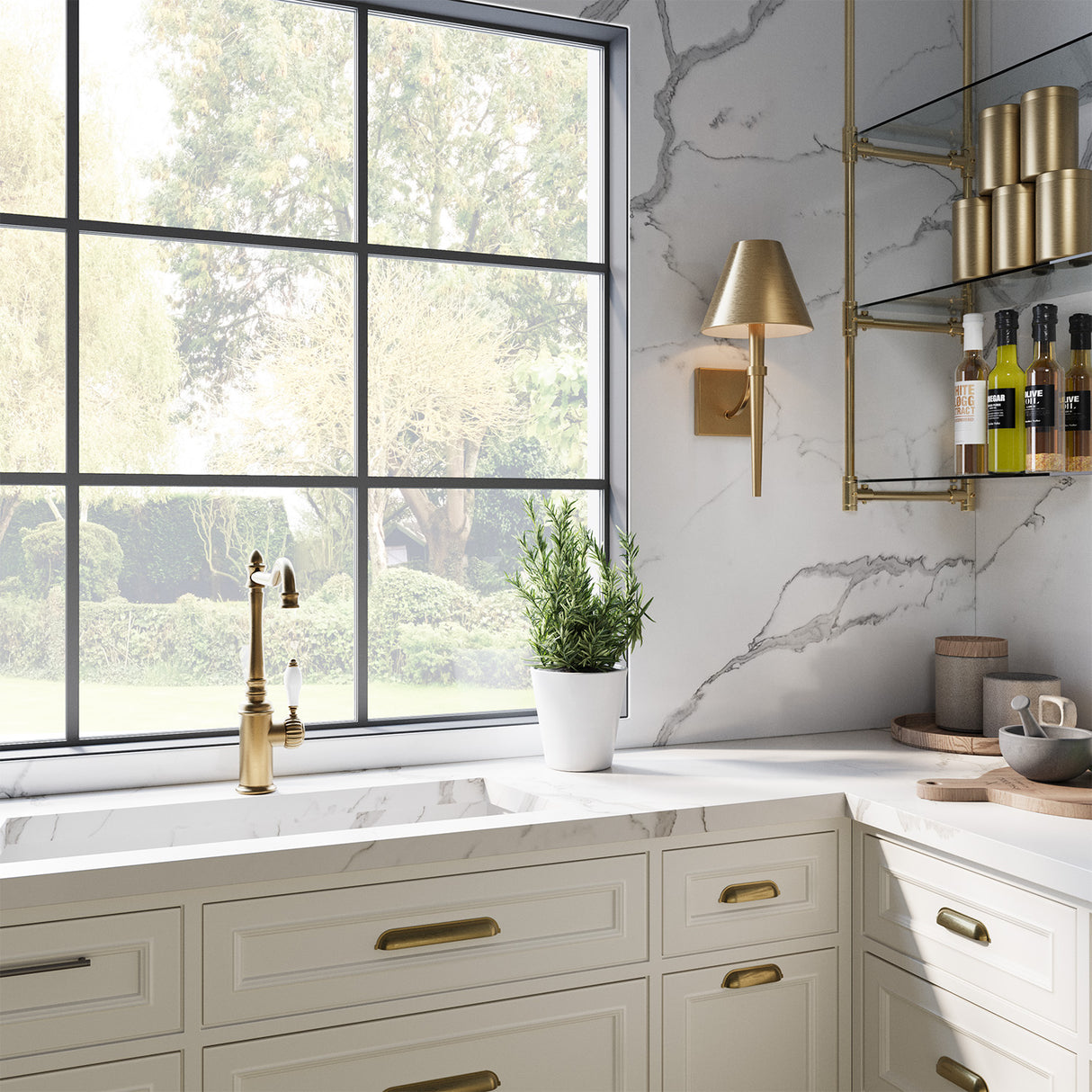 Clara 19" Wall Sconce in Aged Brass shown next to a window in a modern kitchen with marble countertop, backsplash, and gold fixtures.