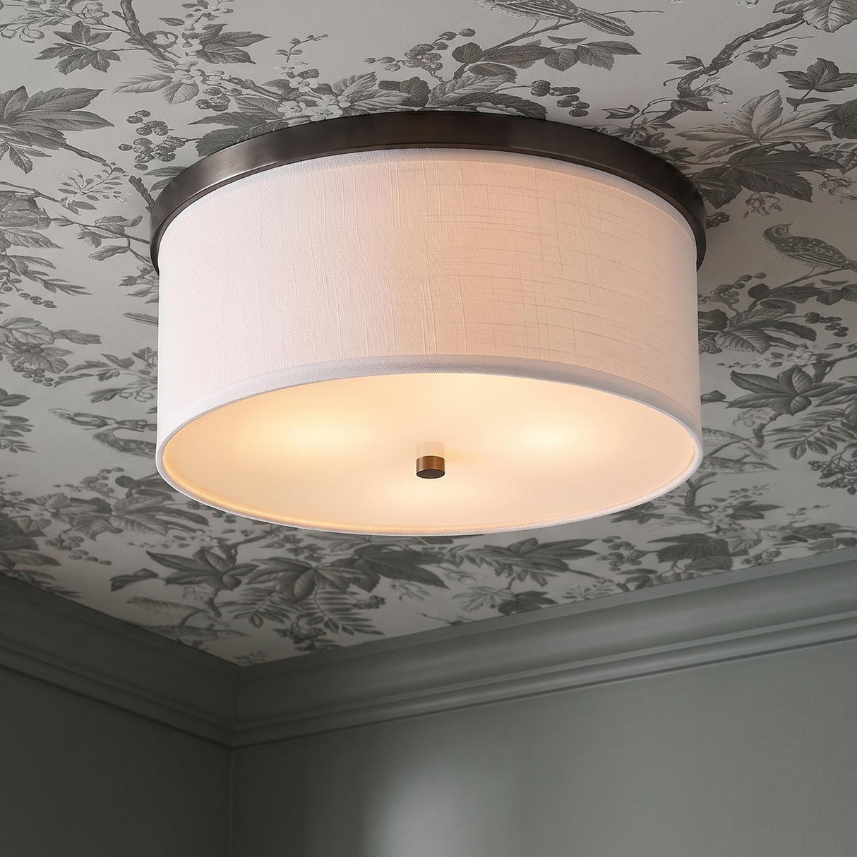 A traditional foyer with the Wells Flush Mount 16", Brushed Bronze featuring a white linen drum shade against botanical floral wallpaper and sage green molding.