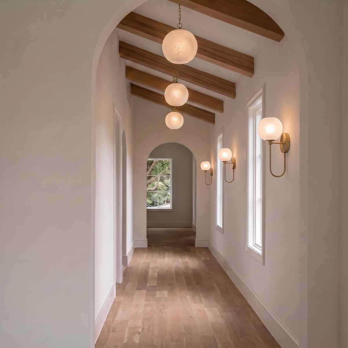 A transitional foyer with the Tova Pendant 14", Matte Brass with Cloud Opal Glass suspended from wood beams above a hallway with light wood flooring.