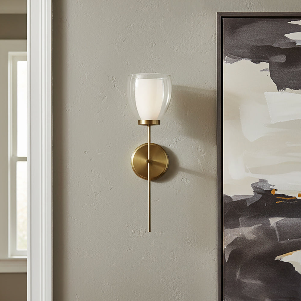 Suri 20" Wall Sconce in aged brass finish, next to a large piece of modern art .