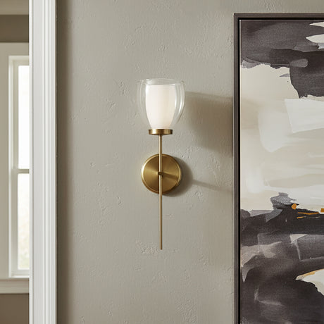 Suri 20" Wall Sconce in aged brass finish, next to a large piece of modern art .