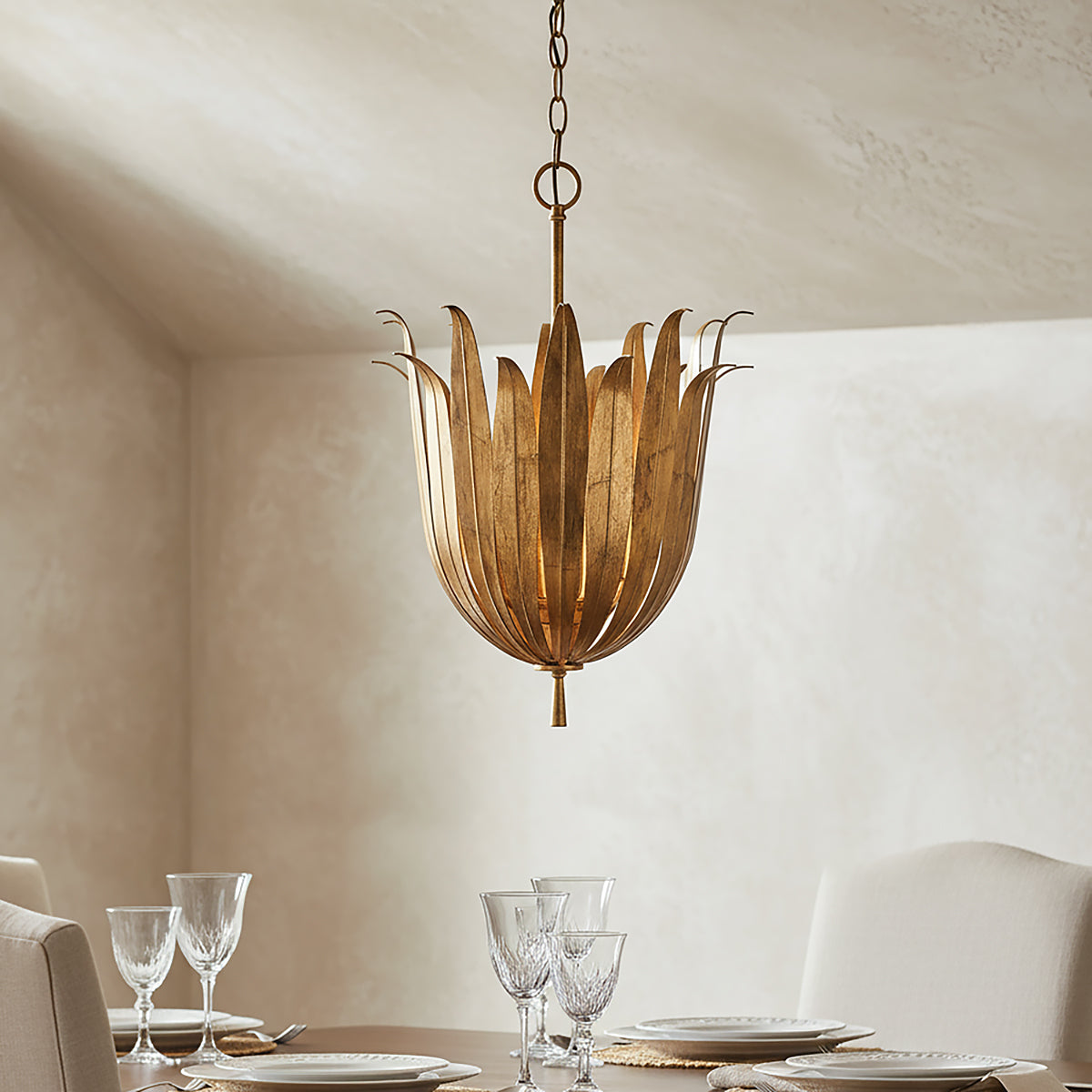 Decorative Cerise brass chandelier 16" hanging above a dining table with glasses and plates.