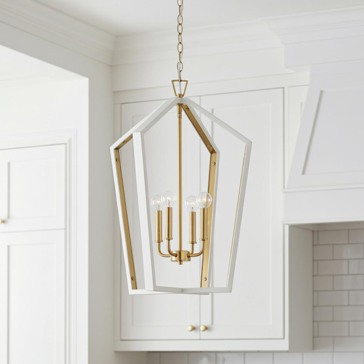 A transitional kitchen features the Talin Lantern Pendant 20 inch White and Matte Brass hanging in the ceiling center before white shaker cabinets and a subway tile backsplash.