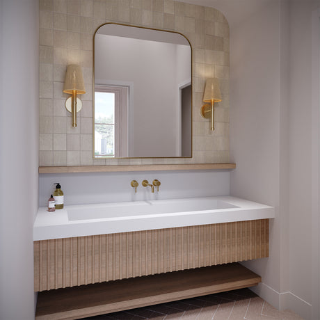 Two 17" tall Evren Wall Sconces shown in a contemporary bathroom flanking an arched mirror, above a large white stone sink and light wood floating vanity.