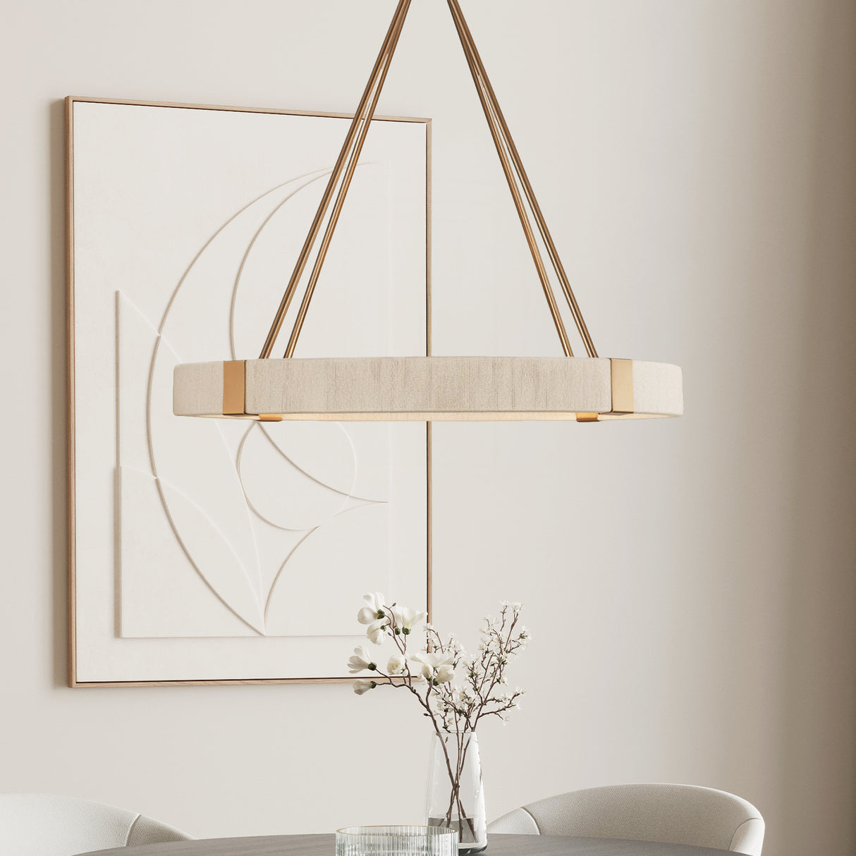 Saltair Ring Chandelier in  Matte Brass with Natural Rope is shown in a dining area in front of modern art.
