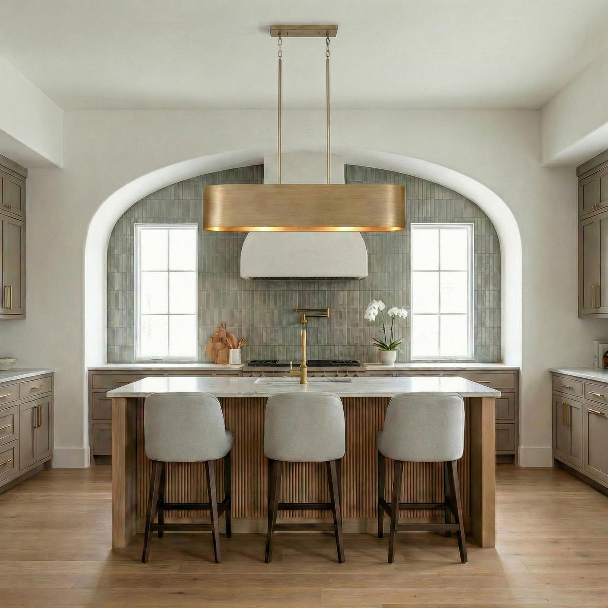 Reed Linear Pendant, Aged Brass linear pendant in a Transitional Kitchen with a white marble island and grey bar stools.