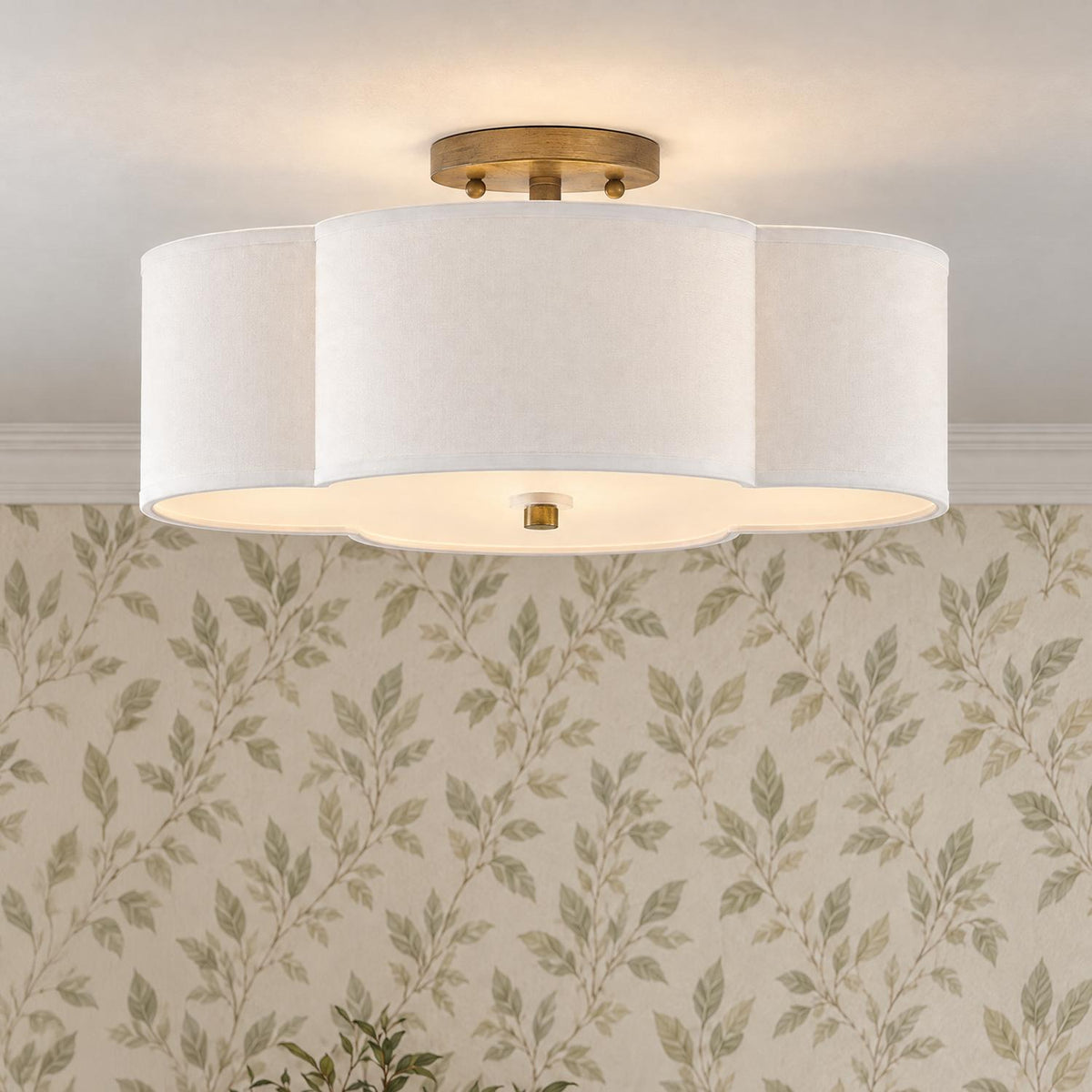 A transitional foyer features the Orla Semi-Flush 18-inch fixture in Brushed Gold with a scalloped white fabric shade against leaf patterned wallpaper.