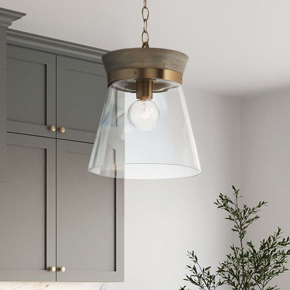 Maren Pendant light 12", Whitewash wood and Matte Brass details with clear glass, is shown in a kitchen with grey-green cabinets.
