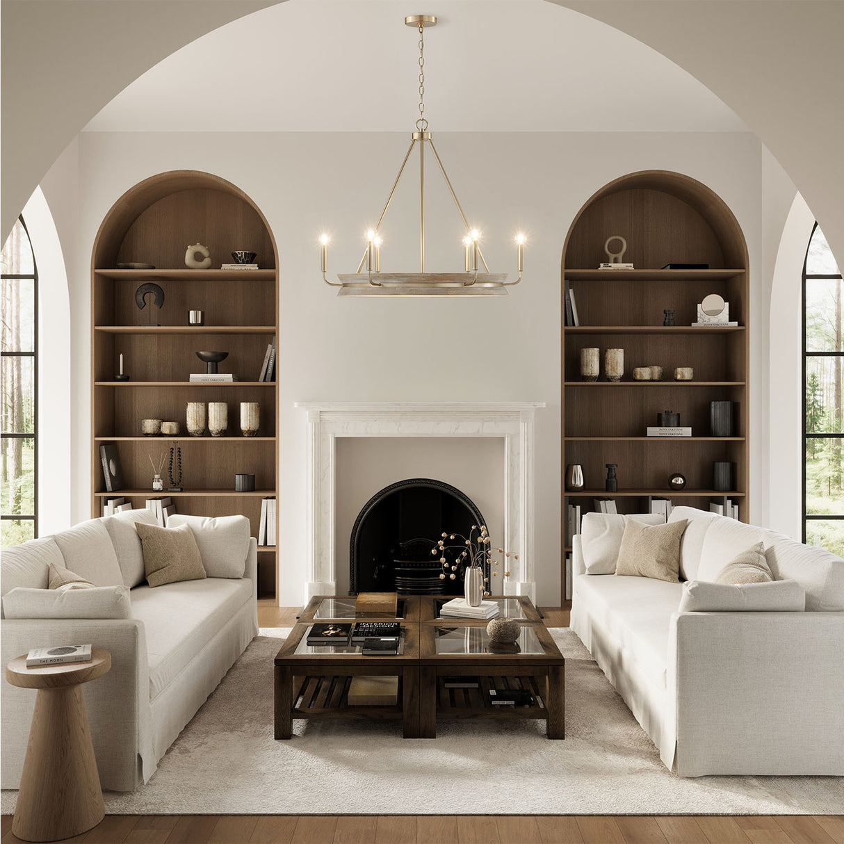 living room with white sofas, wooden arched book shelves and the Maren 6 Light Chandelier 31", in Whitewash and Matte Brass on and glowing.