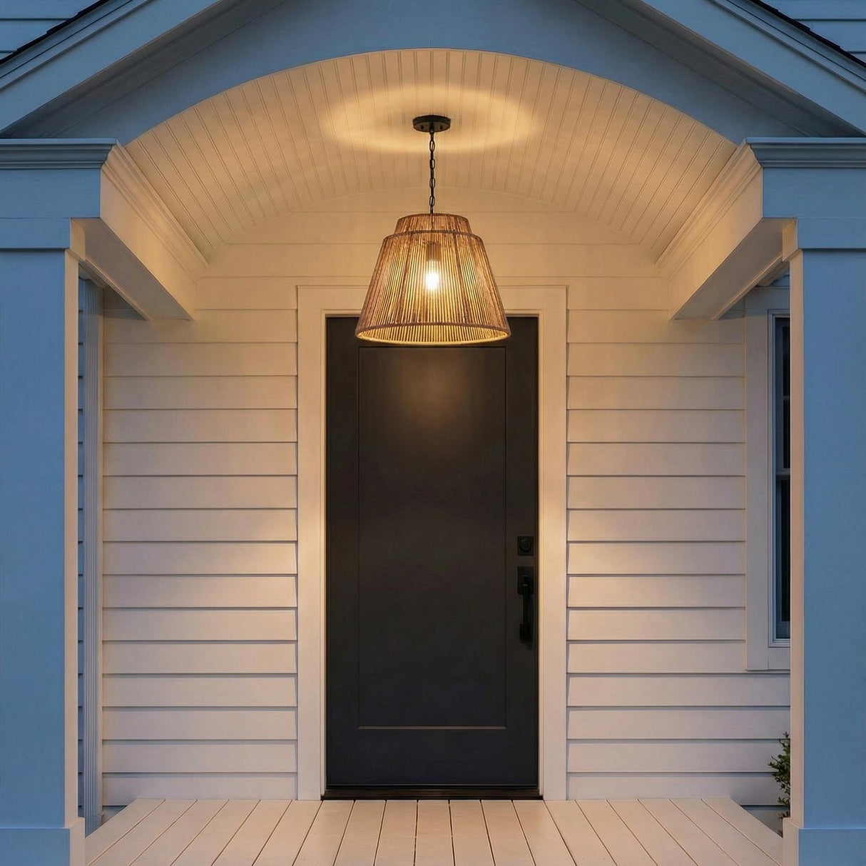 Luma Outdoor Pendant 23", Sienna and Black woven Outdoor Hanging in a Coastal Outdoor area with a black front door and white siding.