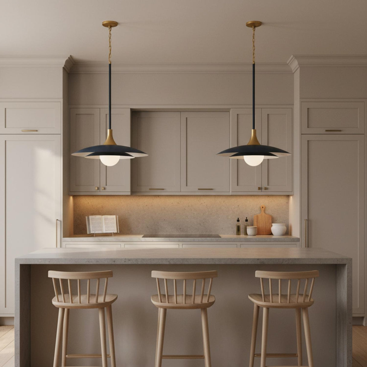 A minimalist kitchen features two Yates LED Pendant 30", Matte Navy fixtures with brass accents and frosted glass globes over a concrete waterfall island and beige cabinets.