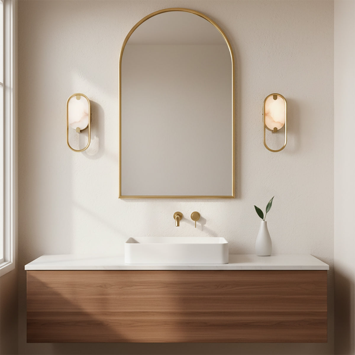 Inez LED Wall Sconce 11, Brass and Alabaster - Two wall sconces with brass frames and alabaster shades flank an arched mirror above a white vessel sink on a wooden vanity.