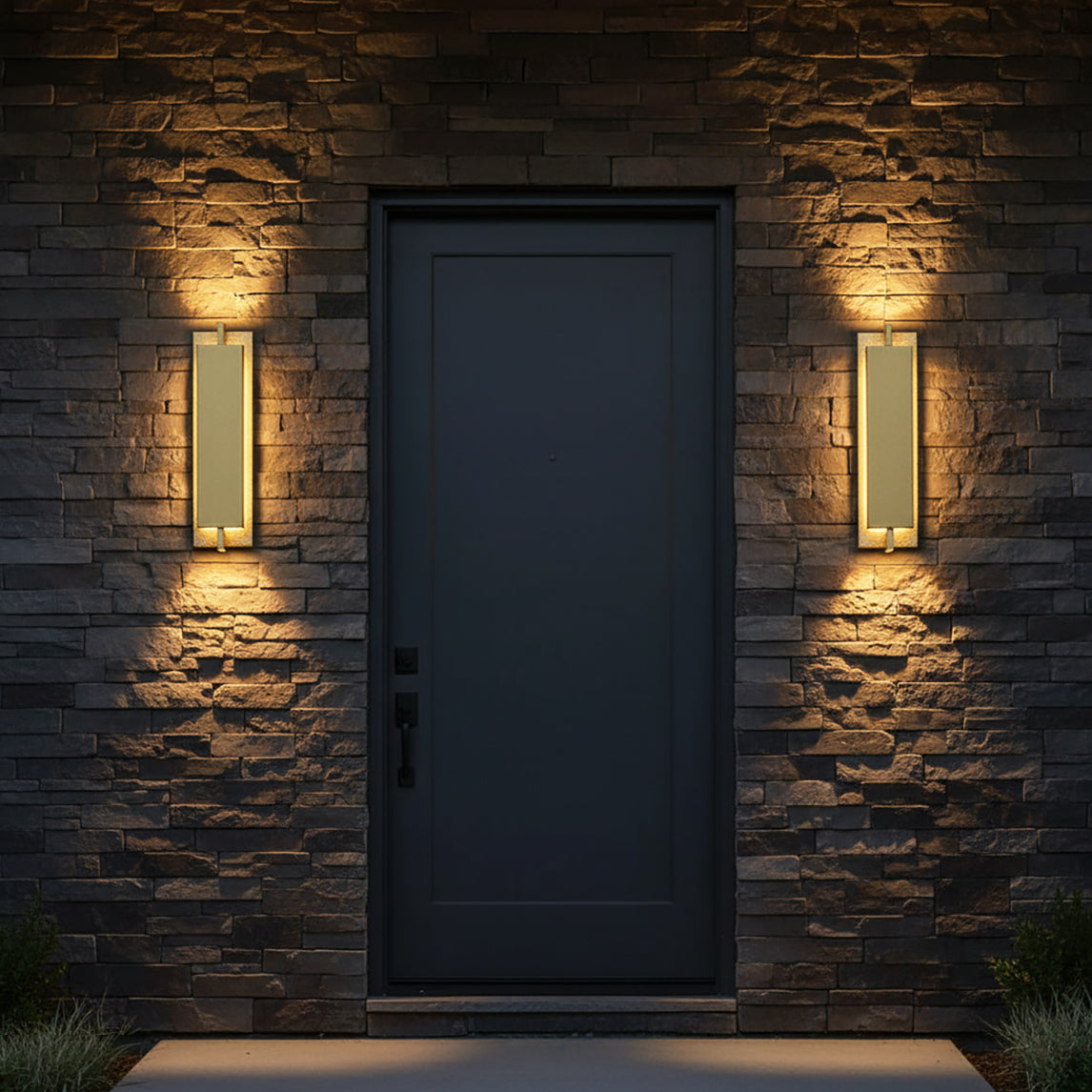 Rye LED Outdoor Wall Light 21, Textured Gold - Two outdoor wall lights flanking a dark front door on a stone wall.