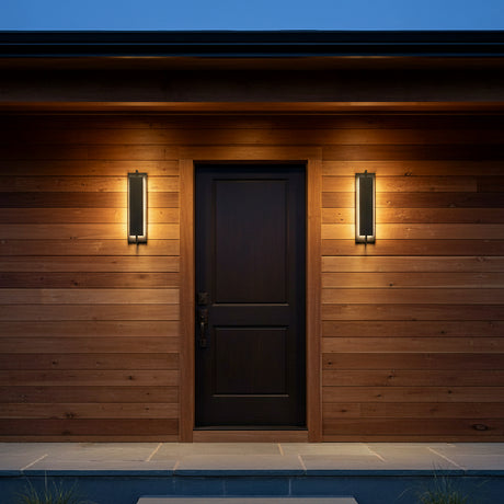Rye LED Outdoor Wall Light 21, Textured Black - Two black sconces illuminate a black door on a wood paneled wall.