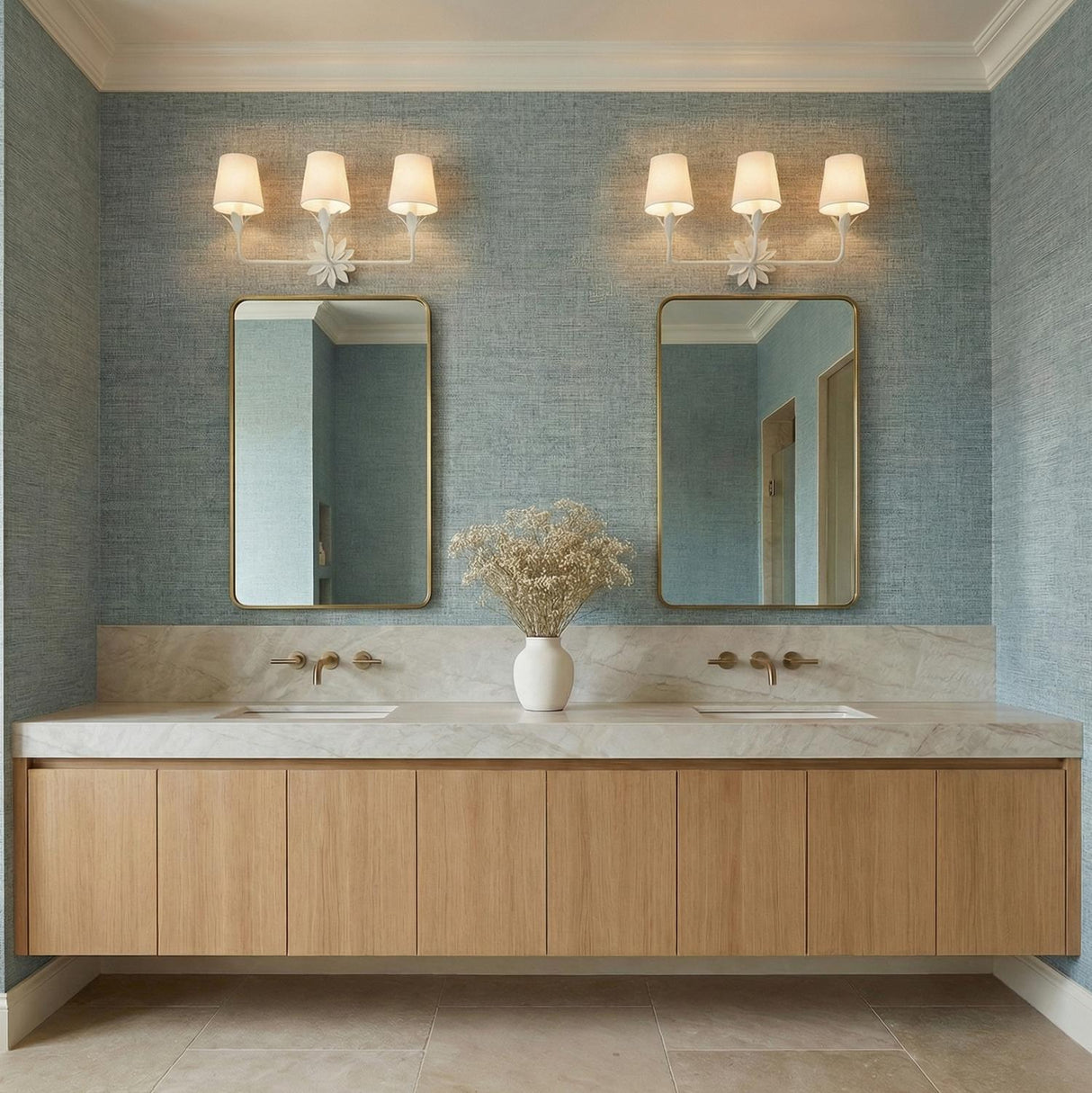 A coastal bathroom with blue grasscloth wallpaper featuring two Ayla 3 Light Vanity, Matte White fixtures with linen shades mounted above gold framed mirrors.