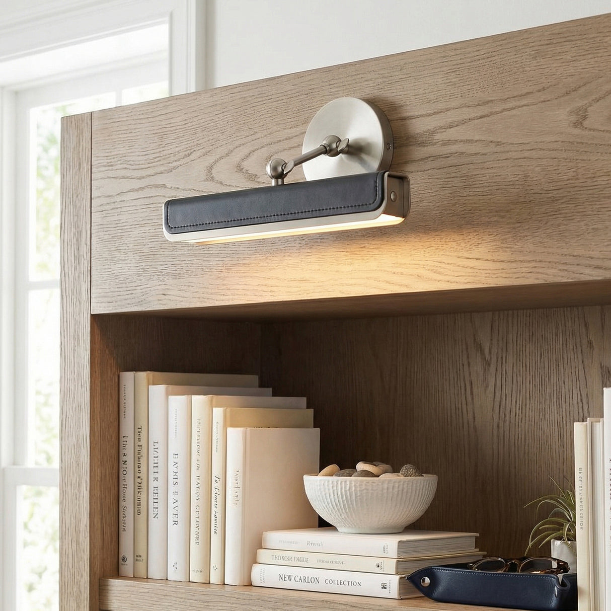 Jarrett LED Picture Light 12", Brushed Nickel and Tuxedo Leather linear wall sconce in a Modern Living Room with a wooden bookshelf.