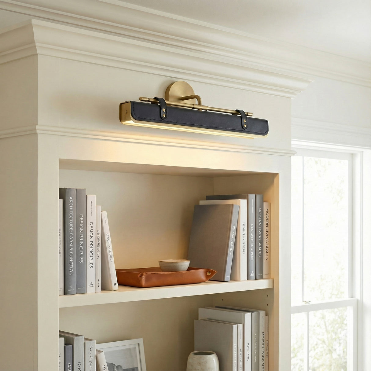 Jarrett LED Wall Light 20" in Aged Brass and Tuxedo Leather, styled in a Transitional Entryway with white shelving.