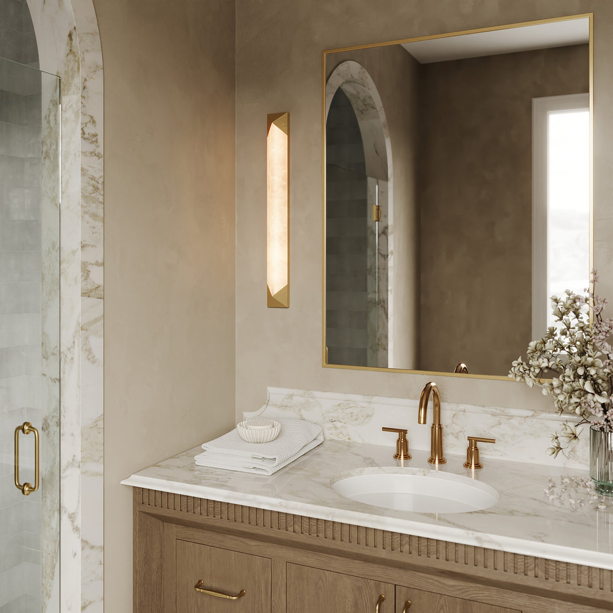 Lunaire LED Wall Sconce 25", Aged Brass and Alabaster shown next to a square gold mirror in a sophisticated modern bathroom.