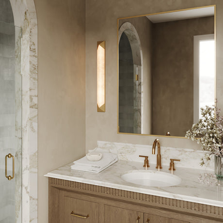 Lunaire LED Wall Sconce 25", Aged Brass and Alabaster shown next to a square gold mirror in a sophisticated modern bathroom.