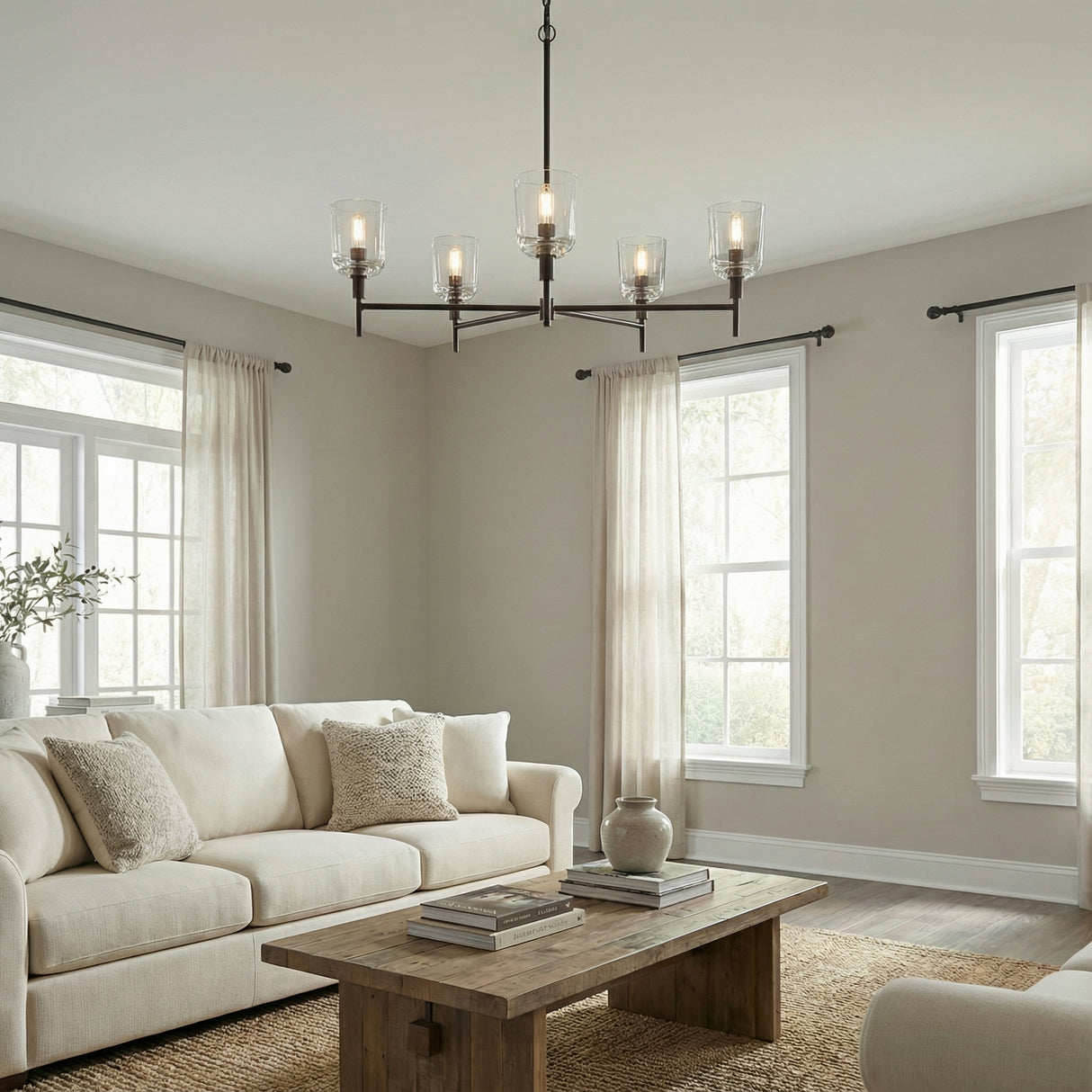 Emrys 5 Light Chandelier 36", Aged Iron linear Chandelier in a Transitional Living Room with a rustic wood coffee table & natural fiber rug.