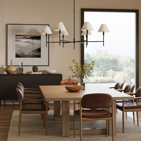 Bryson 6 Light 48" Chandelier in Aged Iron finish with white shades is shown in a modern dining room above an expansive table with seating for 8-10.