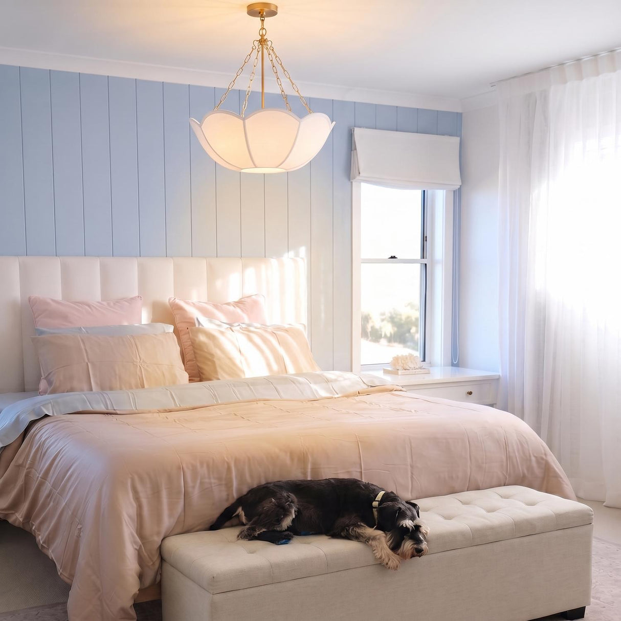 A cottage bedroom featuring a brass pendant with a white linen shade centered along the ceiling above a peach bed and light blue vertical shiplap wall.