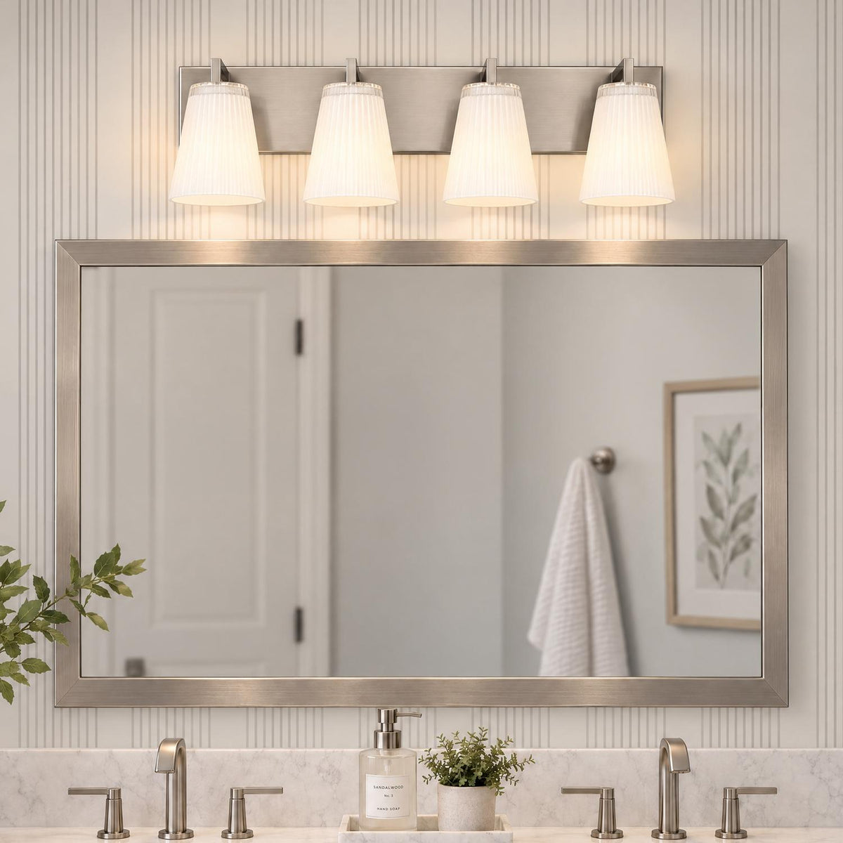 A transitional bathroom features the Margot 4 Light Vanity, Brushed Nickel with white ribbed glass shades mounted above a framed mirror over a marble countertop.