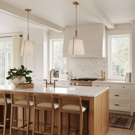 Two Isleton Small 14" wide Pendant lights in Aged Gilded Brass finish are hung above a kitchen island in a modern farmhouse style design.