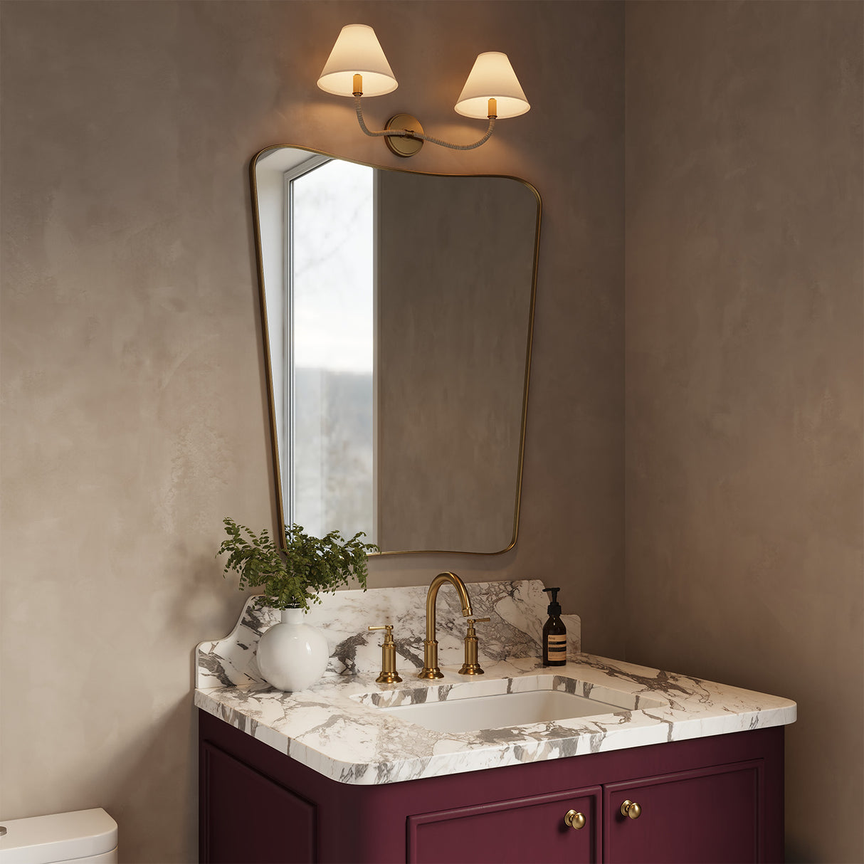 Harlow Double Wall Sconce, Modern Brass with Rattan above a burgundy single vanity with a curvy mirror