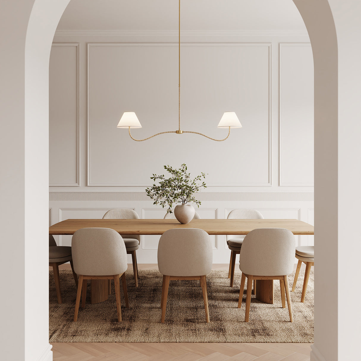 Dining room with wooden table and white chairs, and the Harlow 2 Light Linear Pendant 51", in Modern Brass with Rattan.