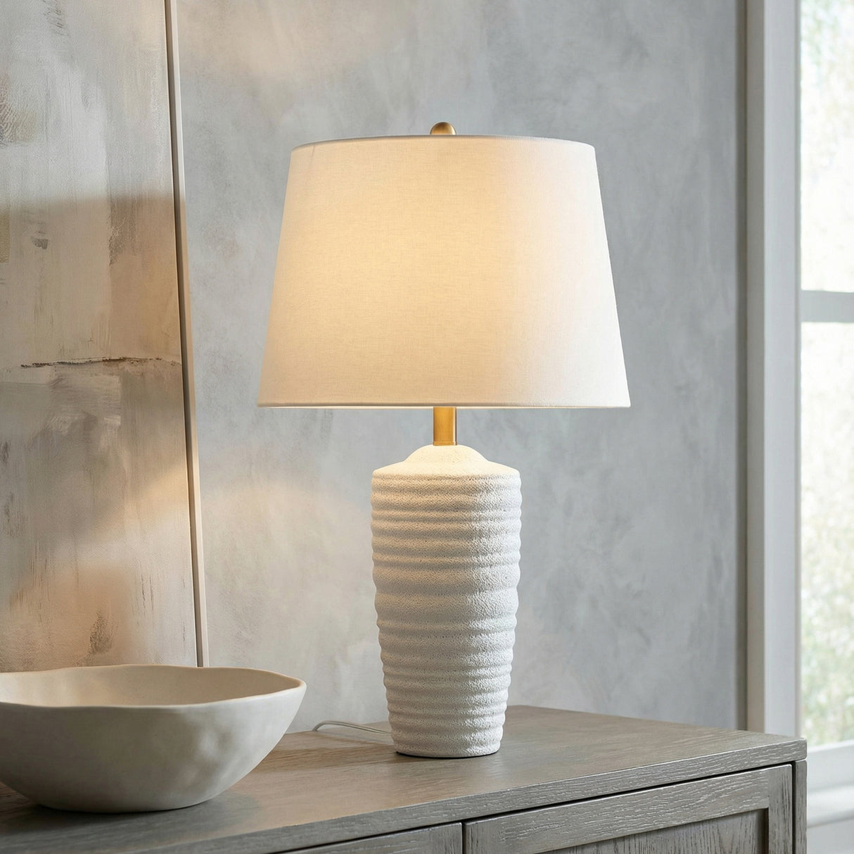 Joyce Table Lamp, Textured White linear Table Lamp in a Transitional Living Room with a grey wood console table and abstract art.