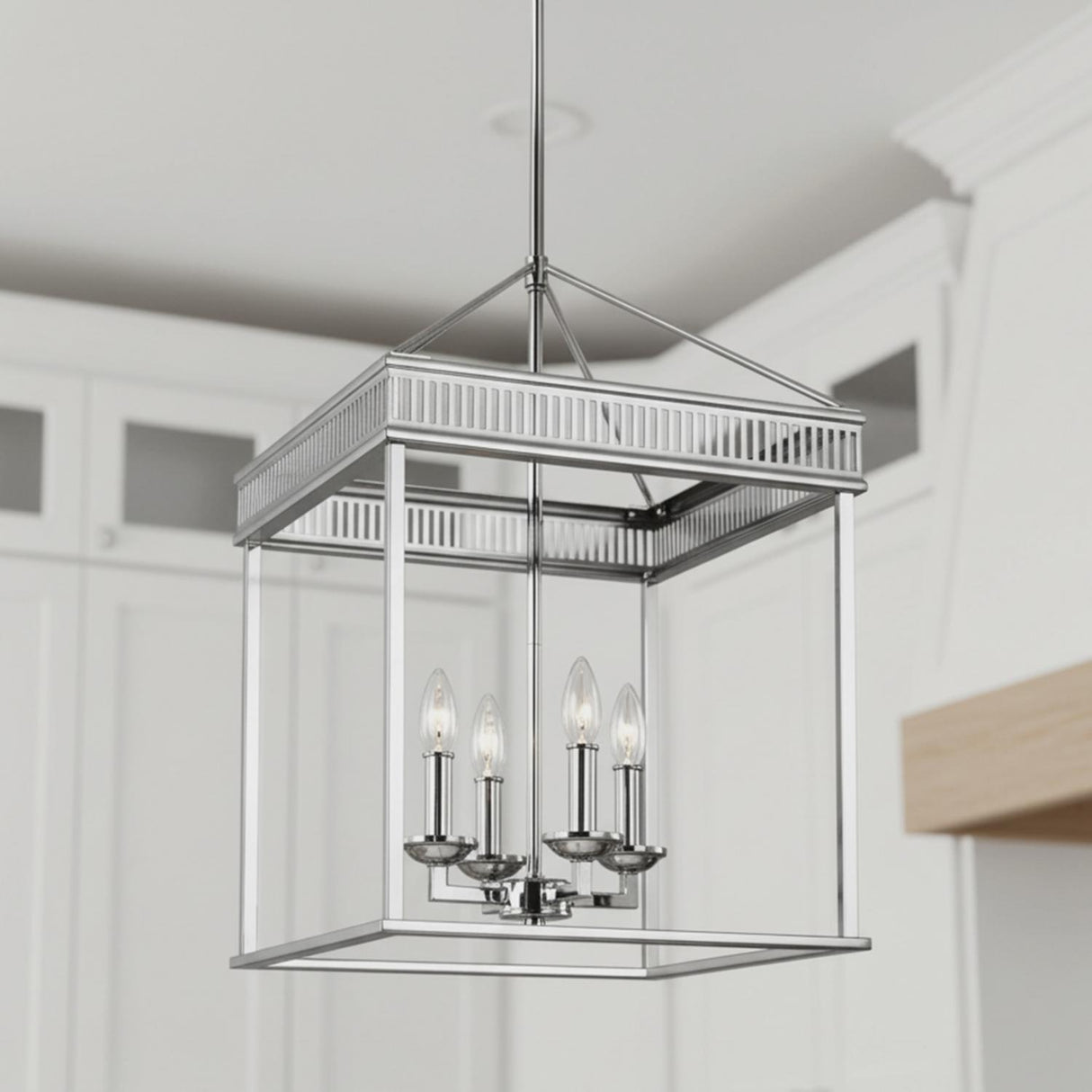 A transitional kitchen features the Rubin Lantern Pendant 16", Polished Nickel hanging along the ceiling in front of white cabinetry with glass-front inserts and a wood-trimmed hood.