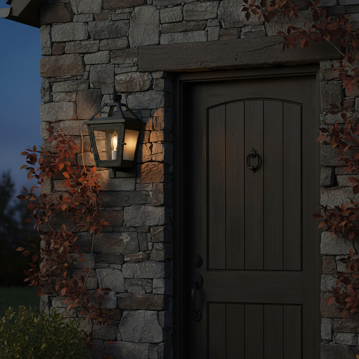 Fairmont Extra Small Outdoor Wall Light 13" - Black lantern light mounted on stone wall next to a dark wood door with autumn foliage.